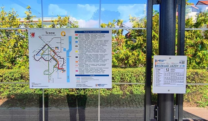 Tablica informacyjna na przystanku autobusowym w Tczewie z mapą sieci komunikacji miejskiej oraz wykazem linii autobusowych; obok znajduje się rozkład jazdy
